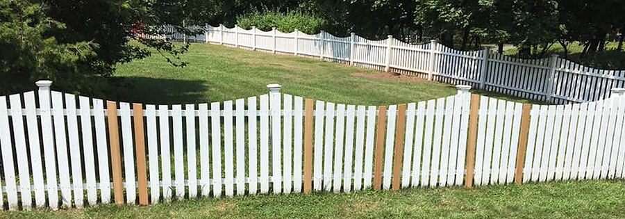 White picket fence cleaned and painted along a lawn