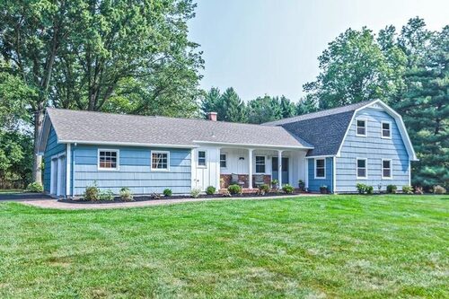 Blue ranch house with white trim and a barn style gable