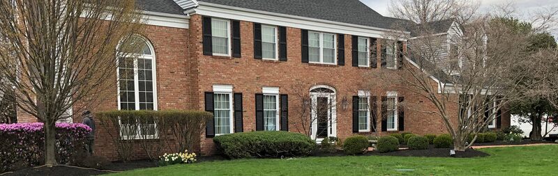 Brick colonial home with white window trim and black shutters