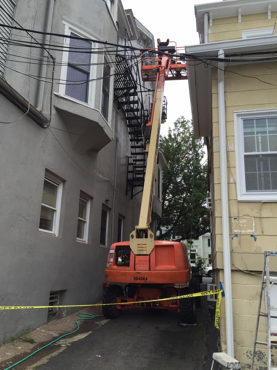 Boom lift set up between two buildings for exterior painting work