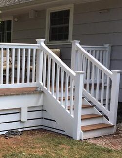 Deck stairs and railing painted white against grey siding