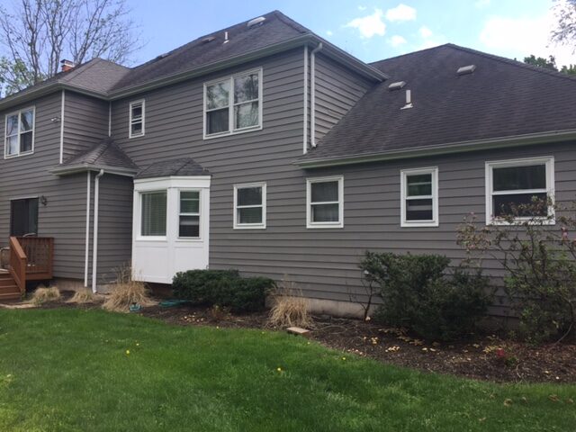 Grey siding and white trim on a cleaned two storey house