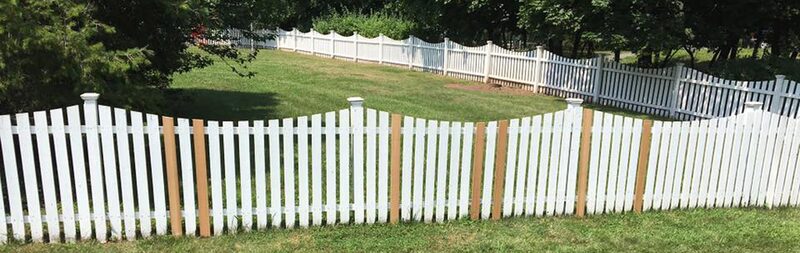 Long white picket fence running along a lawn